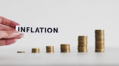 inflation text in front of growing stacks of coins representing increasingly expensive prices, concept of global economy struggling after the covid-19 pandemic