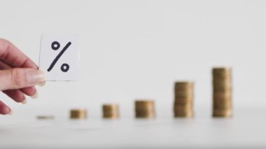 interest rates for loans and mortgages going up conceptual image, percentage symbol with growing stacks of coins representing increasingly expensive cost of financing