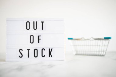 out of stock text on lightbox with empty shopping basket on white background, concept of supply chain shortages and delays after the covid-19 global pandemic