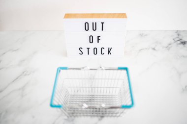 out of stock text on lightbox with empty shopping basket on white background, concept of supply chain shortages and delays after the covid-19 global pandemic