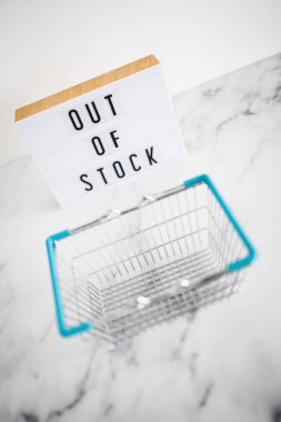 out of stock text on lightbox with empty shopping basket on white background, concept of supply chain shortages and delays after the covid-19 global pandemic