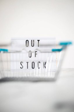 out of stock text on lightbox with empty shopping basket bokeh on white background, concept of supply chain shortages and delays after the covid-19 global pandemic