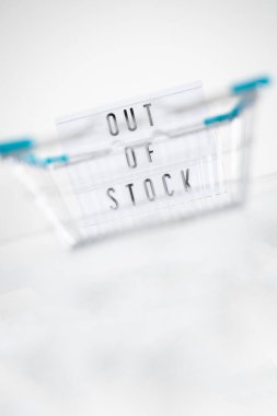 out of stock text on lightbox with empty shopping basket bokeh on white background, concept of supply chain shortages and delays after the covid-19 global pandemic