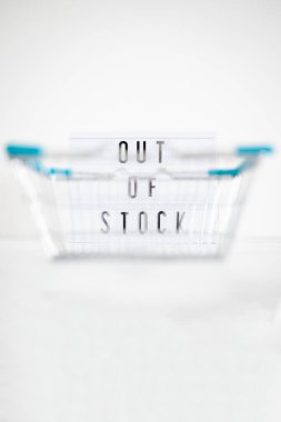 out of stock text on lightbox with empty shopping basket bokeh on white background, concept of supply chain shortages and delays after the covid-19 global pandemic