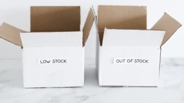 Low stock and out of stock texts on white delivery parcels on white background, concept of supply chain shortages and delays after the covid-19 global pandemic