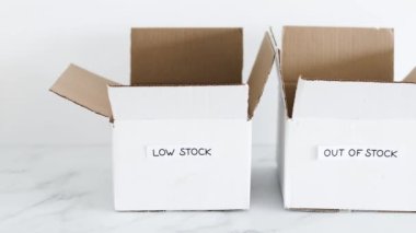 Low stock and out of stock texts on white delivery parcels on white background, concept of supply chain shortages and delays after the covid-19 global pandemic