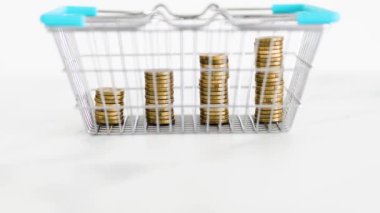 prices going up and rising inflation concept with shopping basket with growing stacks of coins inside of it, global economy struggling after the covid-19 pandemic