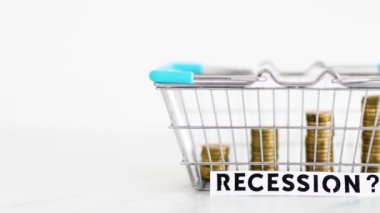 prices going up and rising inflation concept with Recession text in front of shopping basket with growing stacks of coins inside of it, global economy struggling after the covid-19 pandemic