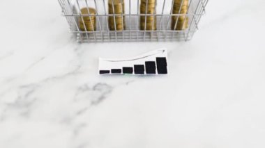 prices going up and rising inflation concept with graph in front of shopping basket with growing stacks of coins inside of it, global economy struggling after the covid-19 pandemic