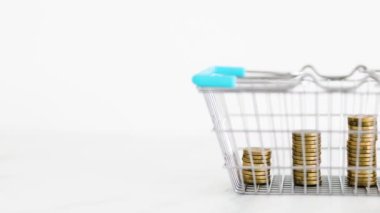 prices going up and rising inflation concept with shopping basket with growing stacks of coins inside of it, global economy struggling after the covid-19 pandemic