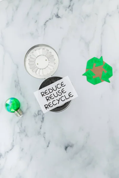 緑の電球とリサイクルアイコンの隣にミニゴミで再利用サインを減らす持続可能性と循環経済の概念 — ストック写真
