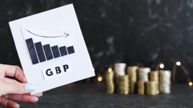 Döviz kurunun kavramsal görüntüsü, grafiği para yığınlarının önünde GBP İngiliz pound metni ile negatif büyüme gösteriyor