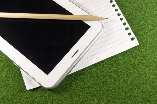 Yeşil çimenlerin üzerinde not defteri ve satır raporları ile dijital tablet — Stok fotoğraf