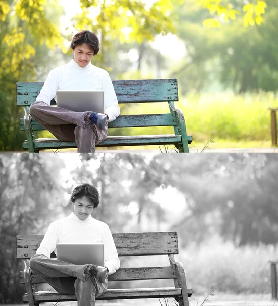 Un jeune homme beau utilisant un ordinateur portable assis sur un banc dans un parc . — Photo