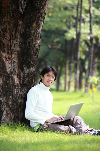 Young man using his laptop on the grass — Stock Photo, Image