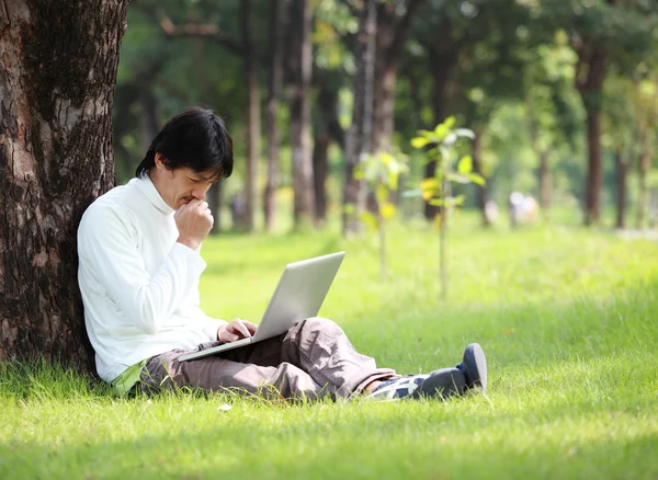 Jeune homme utilisant son ordinateur portable sur l'herbe — Photo