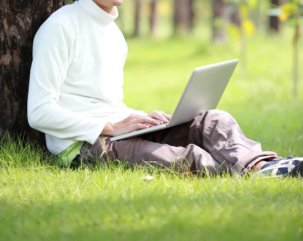 Jeune homme utilisant son ordinateur portable sur l'herbe — Photo