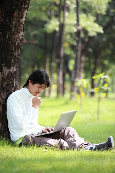 Młody człowiek za pomocą jego laptop na trawie — Zdjęcie stockowe