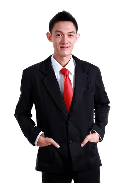 Geschäftsmann lächelt mit roter Krawatte und schwarzem Anzug auf weißem Bac lizenzfreie Stockbilder