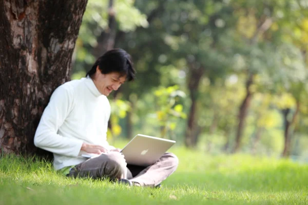 젊은 남자 잔디에 자신의 노트북을 사용 하 여 — 스톡 사진