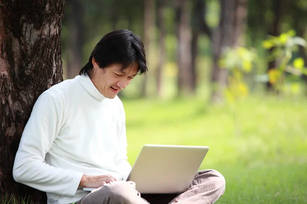 Un tânăr îşi foloseşte laptopul pe iarbă — Fotografie, imagine de stoc