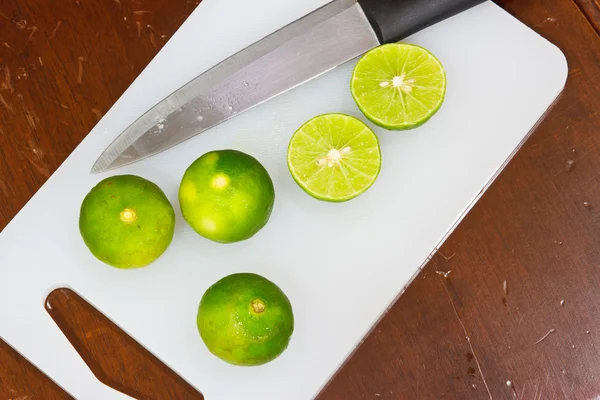 Limas y cuchillo. En una madera —  Fotos de Stock