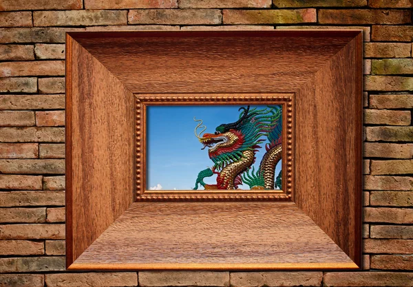 Dragon in picture frame on brickwall — Stock Photo, Image