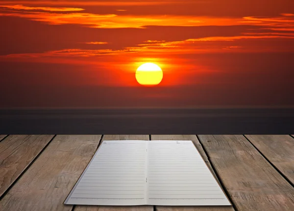 Kniha na dřevěné podlaze se západem slunce — Stock fotografie