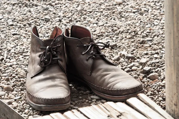 Old brown leather shoes on stone floor — Stock Photo, Image