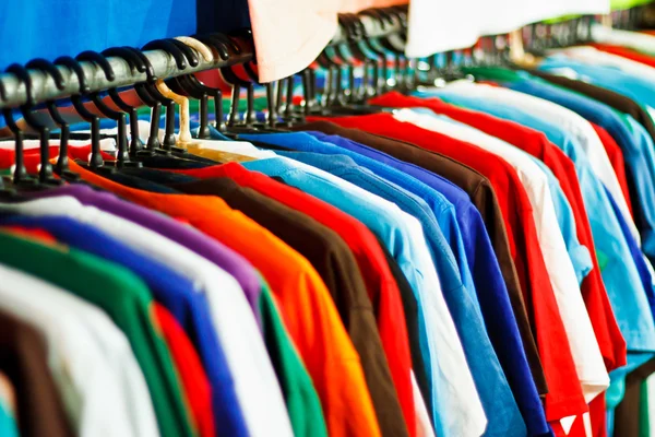 Farben des Regenbogens. Verschiedene lässige Hemden auf Kleiderbügeln lizenzfreie Stockbilder