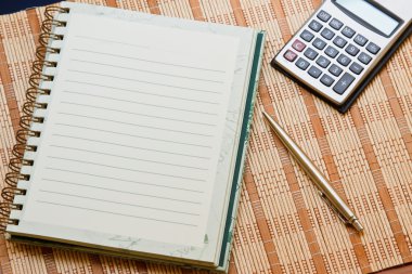 hesap makinesi ile defter & bambu ahşap zemin üzerine kalem