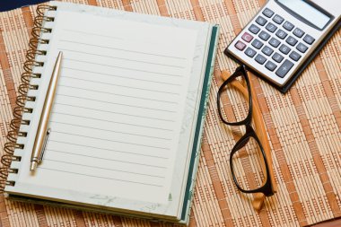 hesap makinesi ile defter & bambu ahşap zemin üzerine kalem