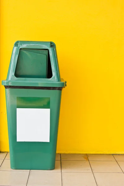 Contenitore di rifiuti di plastica verde con backgrond giallo — Foto Stock
