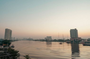 Güneşin doğuşunun ya da batışının şehir görüntüleri. Nehir üzerindeki köprü ve Bangkok Tayland 'da römorkör..
