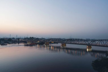 Güneşin doğuşunun ya da batışının şehir görüntüleri. Bangkok Tayland 'da römorkör ile nehir üzerinde köprü.