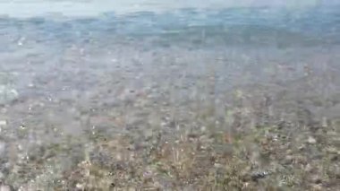 Deniz dalgaları kumda yuvarlanıyor.