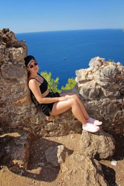 Kız kayalarda oturuyor.