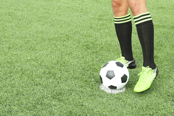 Pelota de fútbol con pie de jugador pateándola — Foto de Stock