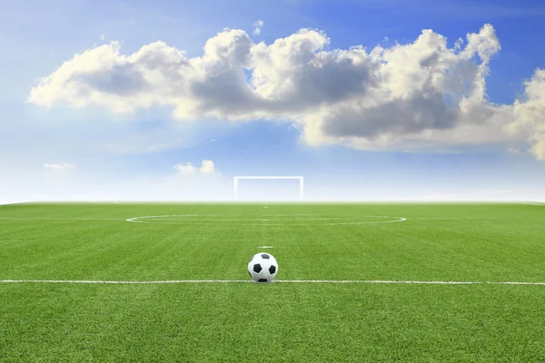 Pallone da calcio sul campo con cielo blu — Foto Stock