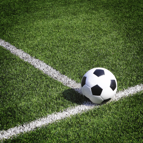 Вид на зеленое полосатое футбольное поле с футбольным мячом
