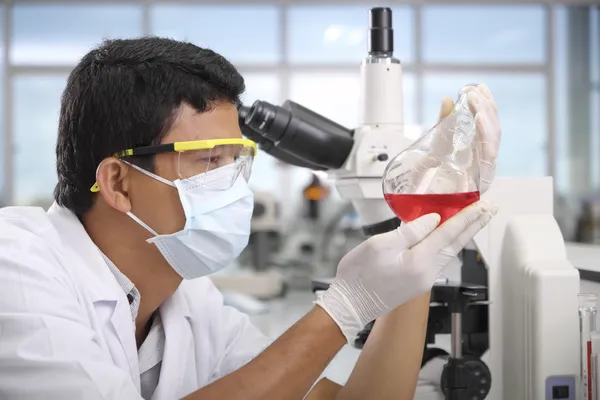 Chemist holding sample of liquid in laboratory — Stok fotoğraf