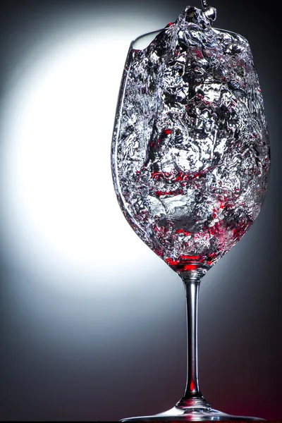 Бокал вина наполнен движущимися жидкими брызгами красного цвета . Лицензионные Стоковые Фото