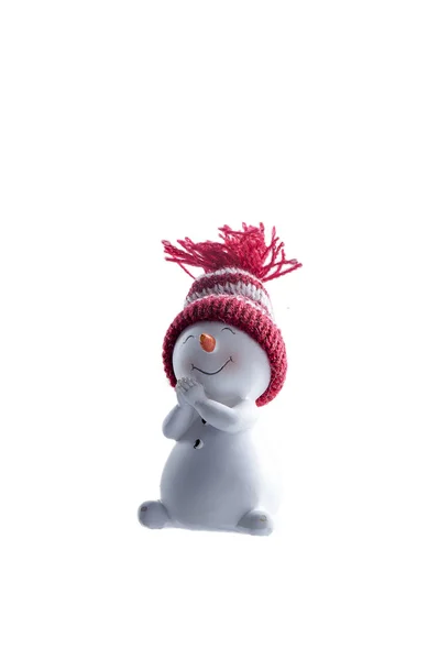 Pupazzo di neve figurina in ceramica in un cappello di maglia rosso e bianco . Foto Stock Royalty Free