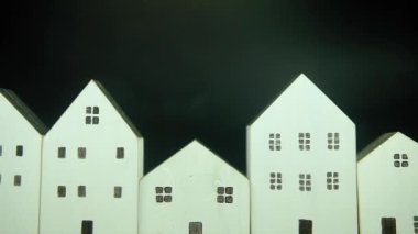 Siyah arka planda pek çok beyaz evin görüntüsü.