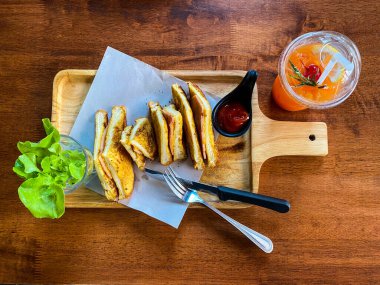 Izgara jambonlu ve peynirli sandviç ve ahşap masada bir bardak portakal suyu.