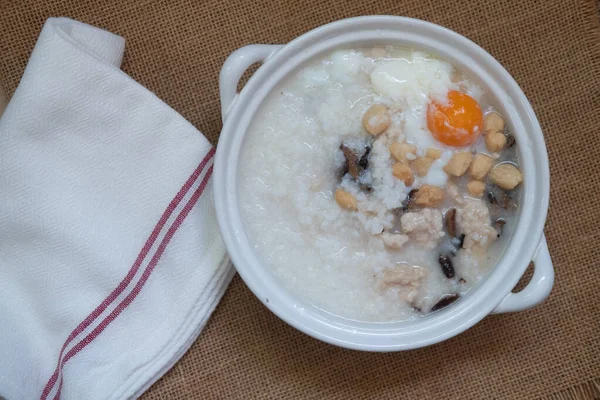米粥配上煮得软的鸡蛋和切碎的猪肉配上酥脆的帕通戈在白土锅里 泰国早餐 — 图库照片