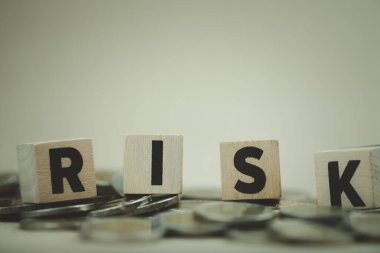 Bir madeni paraya yerleştirilmiş tahtadan bir risk bloğu alfabesi. Mali konsept.