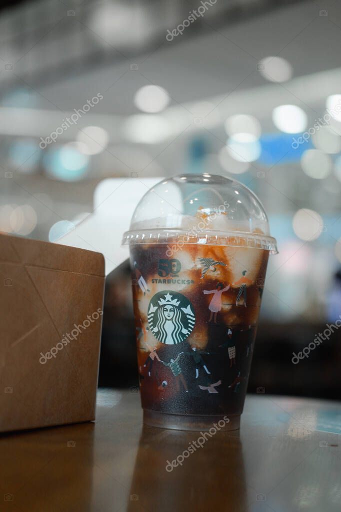 Bangkok, Thailand - November 1, 2021 : Yuzu Cold Brew in a reusable cup with a special 50th anniversary design and a box of cake adding a good freshness during the day at Starbucks coffee