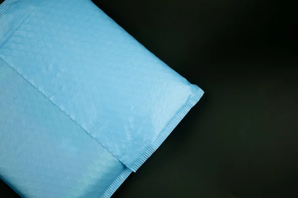 黒い背景にバブルラップ付きブルーのパッド入り封筒 テキストのスペース — ストック写真