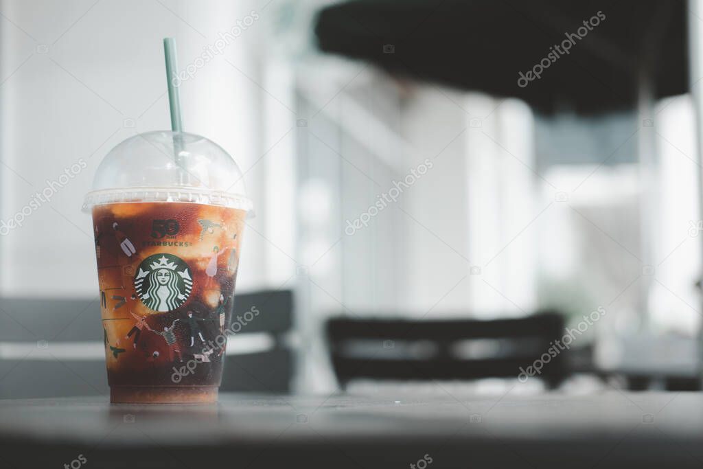 Bangkok, Thailand - November 6, 2021 : Yuzu Cold Brew in a reusable cup with a special 50th anniversary design and a box of cake adding a good freshness during the day at Starbucks coffee